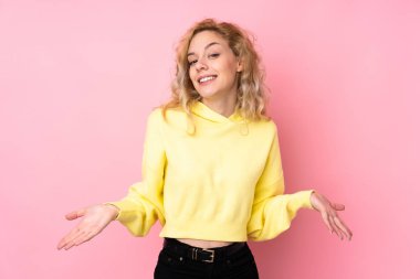 Pembe arka planda izole edilmiş sweatshirt giyen genç sarışın kadın gülümsüyor.