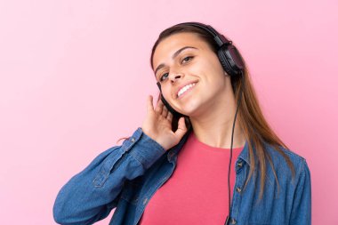 İzole edilmiş pembe duvarda müzik dinleyen genç kız.