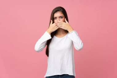 Soyutlanmış pembe arka planı olan genç bir kadın elleriyle ağzını kapatıyor.