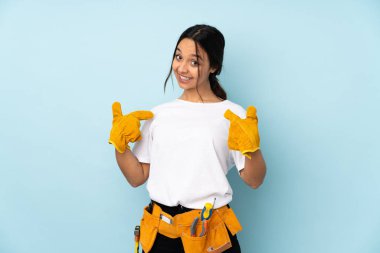 Mavi arka planda izole edilmiş genç elektrikçi kadın gururlu ve kendini beğenmiş.