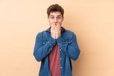 Beyaz bir adam bej arka planda izole edilmiş ve yüzünde sürpriz bir ifade var.