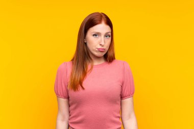 Genç kızıl saçlı kadın izole edilmiş sarı arka plan üzgün