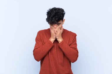 Arjantinli genç adam soyutlanmış mavi arka planda yorgun ve hasta bir ifadeyle