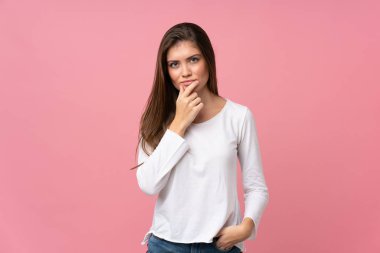 Soyutlanmış pembe arka plan düşünen genç bir kadın.