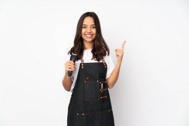 Beyaz arka planda izole edilmiş genç kuaför kadın harika bir fikre işaret ediyor.