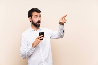 Elinde cep telefonu olan sakallı genç bir adam.