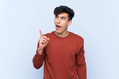 Arjantinli genç adam izole edilmiş mavi arka planda bir fikir düşünüyor.