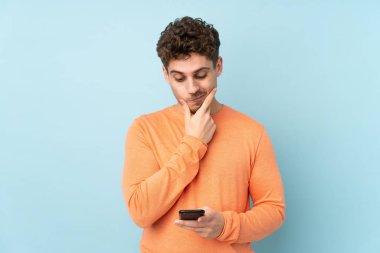 Beyaz adam mavi arka planda izole edilmiş düşünüyor ve bir mesaj gönderiyor.