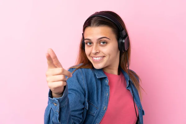 Adolescente menina ouvir música sobre isolado parede rosa — Fotografia de Stock