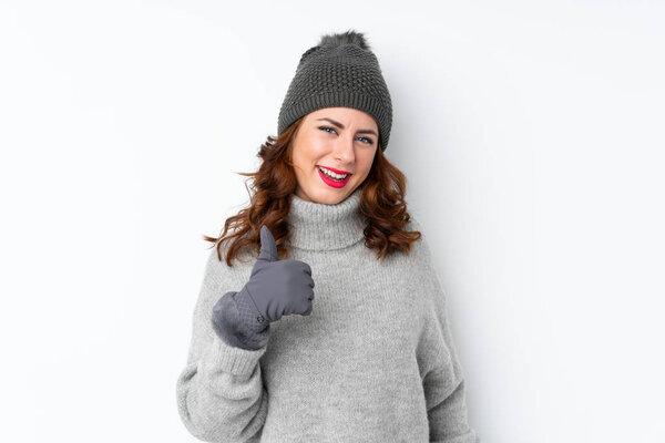 Young Russian woman with winter hat over isolated white background giving a thumbs up gesture