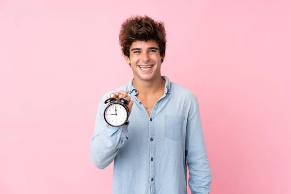 Joven Hombre Caucásico Sobre Fondo Rosa Aislado Sosteniendo Reloj Despertador — Foto de Stock