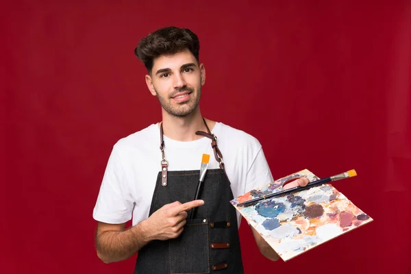 Jovem Sobre Fundo Isolado Segurando Uma Paleta Apontando — Fotografia de Stock