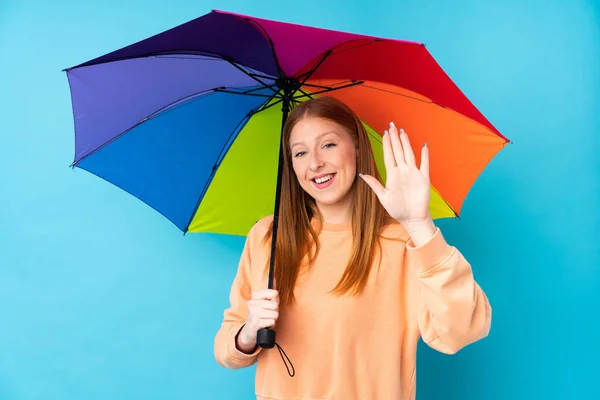 Joven Pelirroja Sosteniendo Paraguas Sobre Una Pared Aislada Saludando Con — Foto de Stock