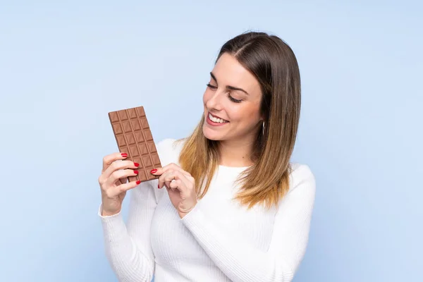 Mladá Blondýna Žena Přes Izolované Modré Pozadí Čokoládovou Tabletu Šťastný — Stock fotografie