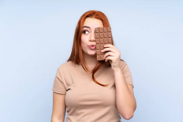 Redhead Teenager Dívka Přes Izolované Modré Pozadí Čokoládovou Tabletu Překvapený — Stock fotografie
