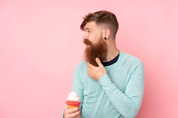 Рыжий Длинной Бородой Держит Мороженое Корнета Изолированном Розовом Фоне Думая — стоковое фото