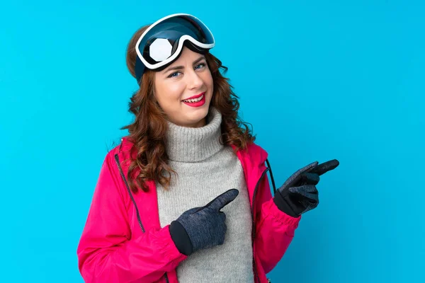 Sciatore Donna Con Occhiali Snowboard Sopra Isolato Muro Blu Puntando — Foto Stock