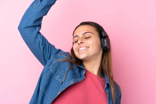 Adolescente chica escuchando música y bailando sobre aislado rosa wal — Foto de Stock