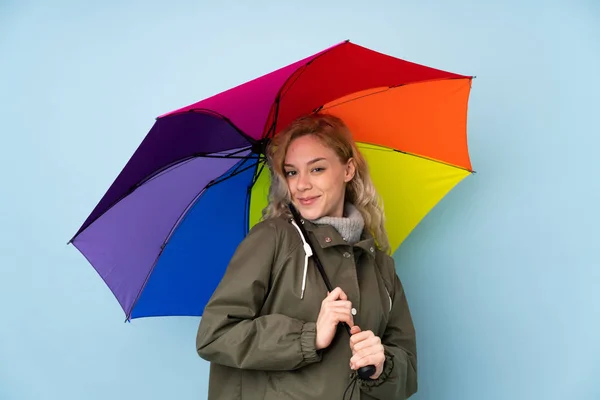 Mujer sosteniendo un paraguas aislado sobre fondo azul — Foto de Stock