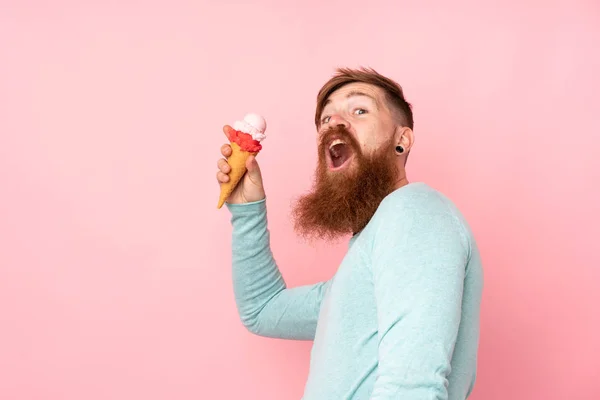Рыжий с длинной бородой держит корнет мороженое над изолом — стоковое фото