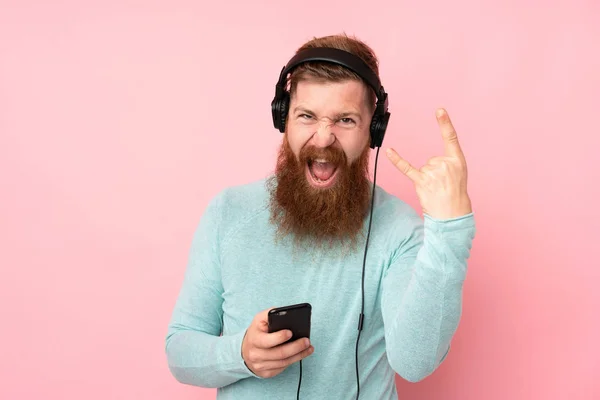 Roodharige Man Met Lange Baard Geïsoleerde Roze Achtergrond Luisteren Muziek — Stockfoto