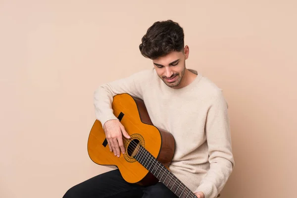 Jongeman met gitaar over geïsoleerde achtergrond — Stockfoto