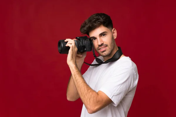 年轻男子用专业相机超越孤立的背景 — 图库照片