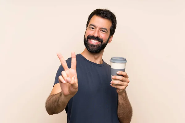 Mężczyzna Brodą Trzymający Kawę Uśmiechniętą Pokazującą Znak Zwycięstwa — Zdjęcie stockowe