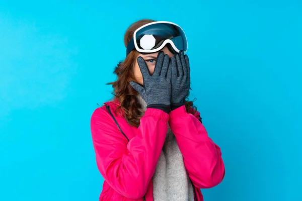 Narciarka Okularami Snowboardowymi Odizolowanej Niebieskiej Ścianie Pokrywającej Oczy Patrzącej Przez — Zdjęcie stockowe