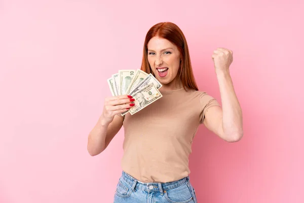 Joven Pelirroja Sobre Aislado Rosa Fondo Tomando Montón Dinero — Foto de Stock