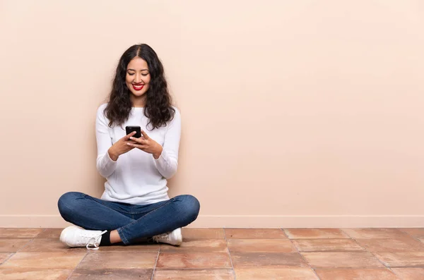 Junge Frau Sitzt Auf Dem Boden Und Sendet Eine Nachricht — Stockfoto