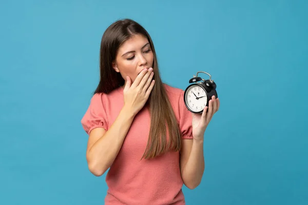 Ung Kvinna Över Isolerad Blå Bakgrund Håller Vintage Väckarklocka — Stockfoto