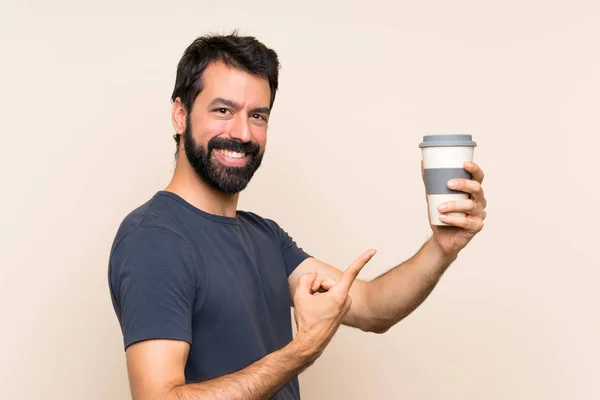 留着胡子的男人拿着咖啡指着咖啡 — 图库照片