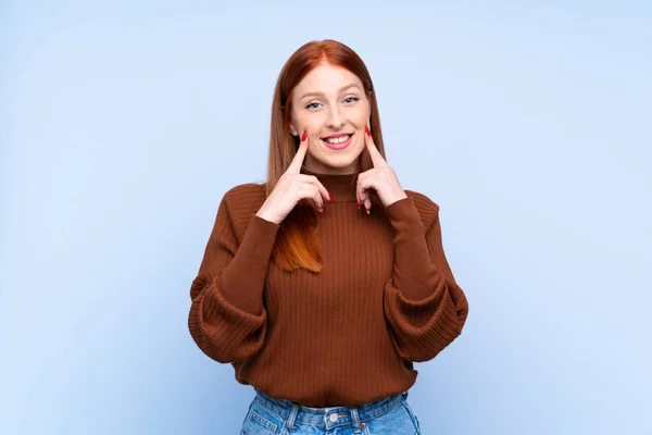 Ung Rödhårig Kvinna Över Isolerad Blå Bakgrund Ler Med Ett — Stockfoto