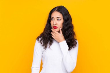 Karma ırk kadını, izole edilmiş sarı arka planda bir fikir düşünüyor.