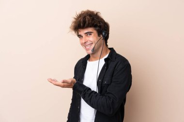 Telemarketer adam izole bir arka planda bir kulaklıkla çalışıyor. Davet etmek için ellerini yana uzatıyor.