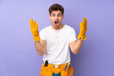 Genç elektrikçi, mor arka planda izole edilmiş, şaşırmış bir yüz ifadesi var.