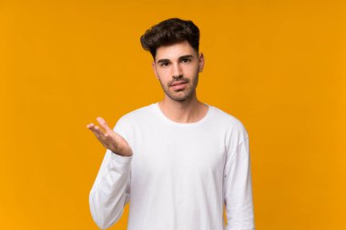 İzole edilmiş turuncu arka planı olan genç adam şüpheli hareketler yapıyor.