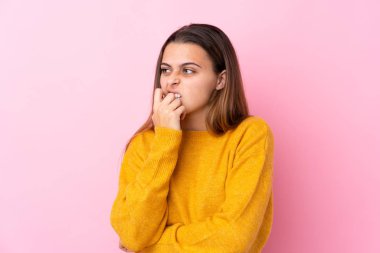Sarı kazaklı genç bir kız pembe arka planda izole edilmiş gergin ve korkmuş
