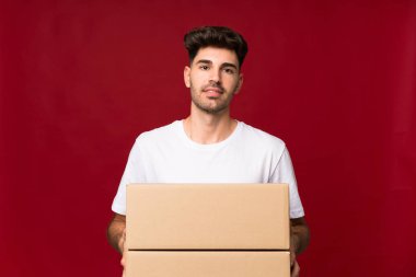 Tecrit edilmiş genç bir adam başka bir yere taşımak için bir kutu tutuyor.