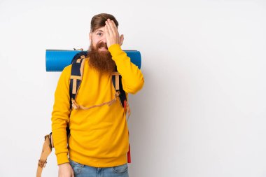 İzole edilmiş beyaz arka planı olan büyük bir sırt çantasıyla genç dağcı adam, bir gözü eliyle kapatıyor.