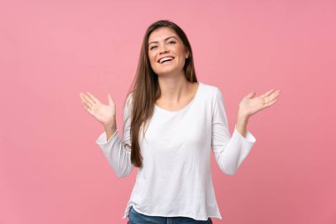 Soyutlanmış pembe arka planı olan genç bir kadın çok gülümsüyor.