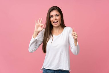 Soyutlanmış pembe arka planda genç bir kadın işaret ve işaret işareti gösteriyor.