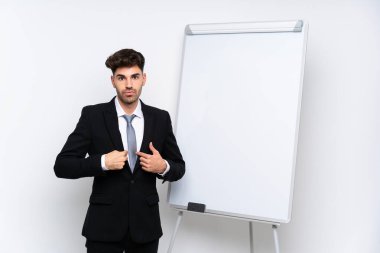 Genç iş adamı beyaz tahtada yüz ifadesiyle bir sunum yapıyor.