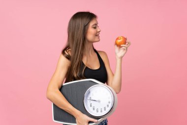 Tartı makinesi olan genç bir kız ve izole edilmiş bir elma.