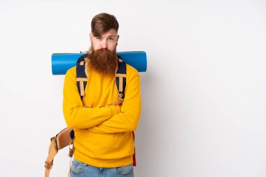 İzole edilmiş beyaz arka planda büyük bir sırt çantası olan genç dağcı. Üzgün.