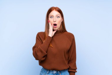 Genç, kızıl saçlı, soyutlanmış, mavi arka planı olan kadın sağa bakarken şaşırmış ve şok olmuştu.