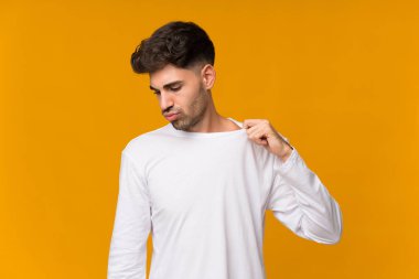 Genç adam turuncu arka planda, yorgun ve hasta bir ifadeyle.