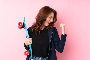 Genç Rus kadın pembe arka planda paten kayıyor ve zafer jestleri yapıyor.