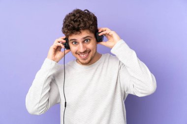 Mor arka planda izole edilmiş beyaz adam müzik dinliyor.